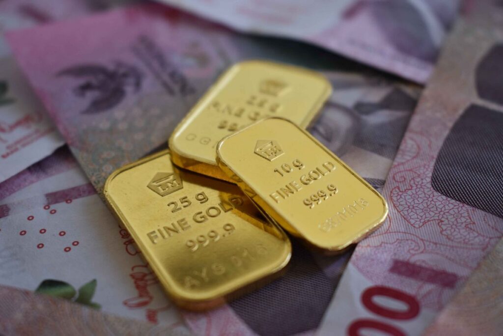 Batang emas di atas uang Rupiah, simbol investasi emas