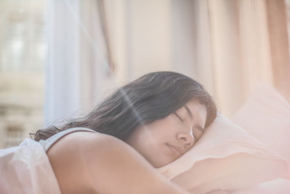 Wanita tidur nyenyak di kasur dengan cahaya pagi
